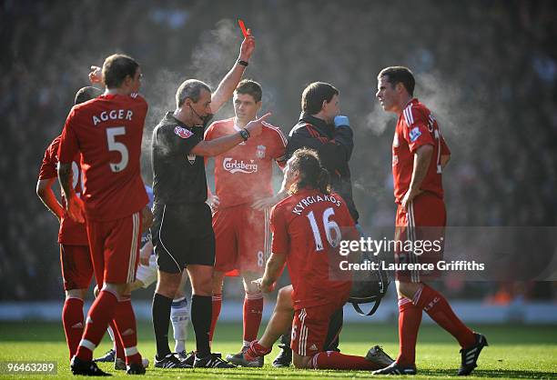 Referee Martin Atkinson shows a red card to Sotiros Kyrgiakos of Liverpool during the Barclays Premier League match between Liverpool and Everton at...