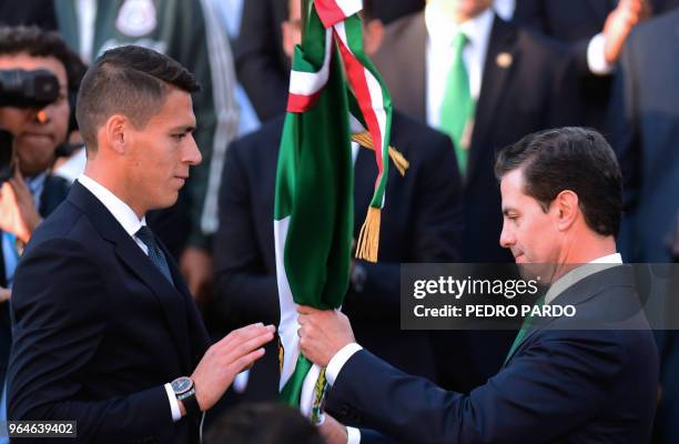 Mexican President Enrique Pena Nieto hands the Mexican national flag to national football team player Hector Moreno during a send-off ceremony at the...