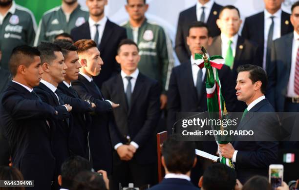 Mexican President Enrique Pena Nieto hands the national flag to Mexico's national football team players during a send-off ceremony at the Los Pinos...