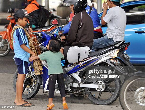 To go with AFP story by Glenda Kwek: INDONESIA-CHILDREN-CRIME-MURDER-POVERTY Hendrawan holds his sister Aimatul Amelia as they work on the street at...