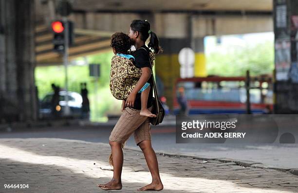 To go with AFP story by Glenda Kwek: INDONESIA-CHILDREN-CRIME-MURDER-POVERTY A woman cradles a toddler as she sings on the street to earn her...