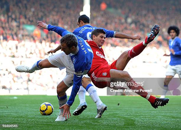 Steven Gerrard captain of Liverpool is taken out by Phil Neville captain of Everton during the Barclays Premier League match between Liverpool and...