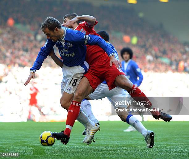 Steven Gerrard captain of Liverpool is taken out by Phil Neville captain of Everton during the Barclays Premier League match between Liverpool and...