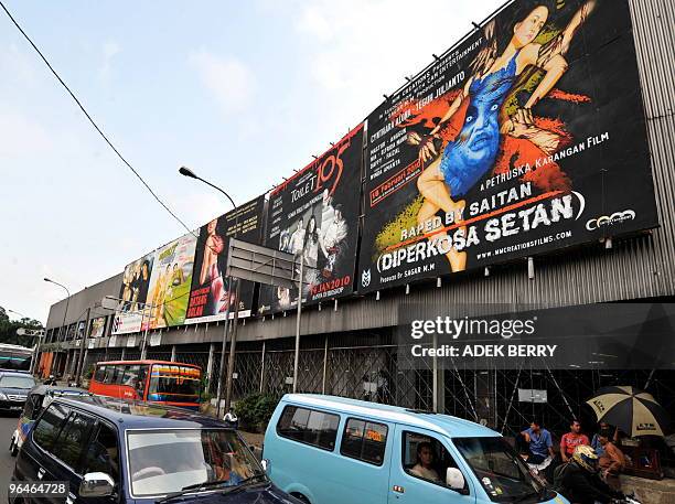 Motorists pass a giant poster advertising the Indonesian movie "Hantu Puncak Datang Bulan" or "The Menstruating Ghost of Puncak" in Jakarta on...