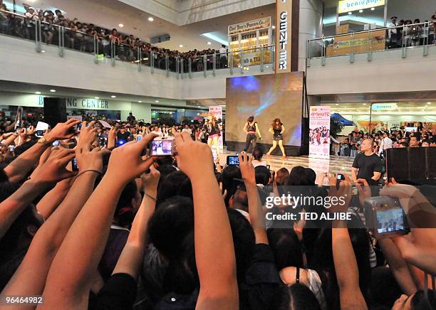 Fans of South Korean girl group '4minute' take photos during a performance at a mall in Manila on February 6 as part of their mall tour. The group is...