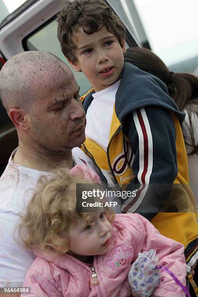 An Israeli man splattered with blood carries two children away from the site of a mine explosion at the Golan Heights, north of Israel, on February...