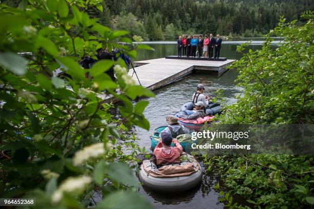 People sit on rafts while fly fishing on Nita Lake as delegates and ministers pose for photographs on a dock following a G7 development ministers...