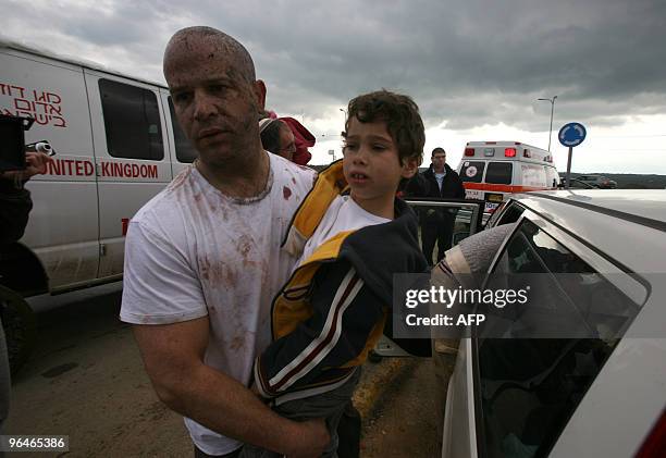 An Israeli man splattered with blood carries a young boy away from the site of a mine explosion at the Golan Heights, north of Israel, on February 6,...