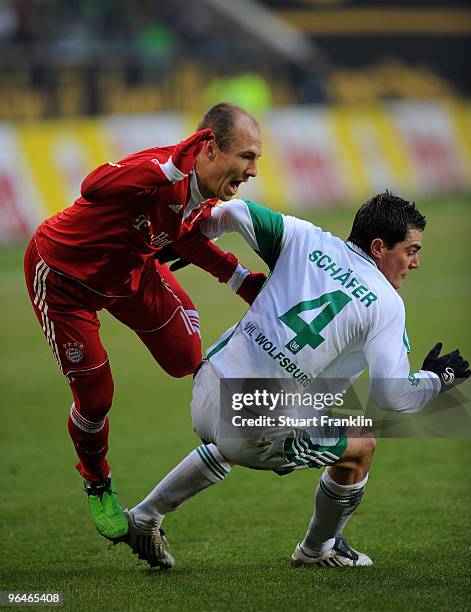 Arjen Robben of Muenchen is challenged by Marcel Schaefer of Wolfsburg during the Bundesliga match between Vfl Wolfsburg and FC Bayern Muenchen at...