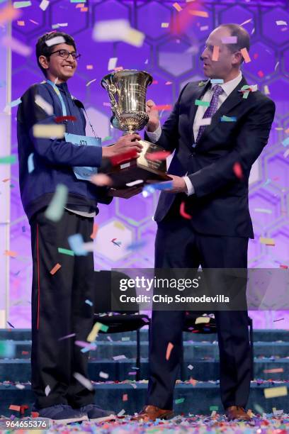 Karthik Nemmani poses with the championship trophy and E.W. Scripps Company CEO Adam Symson after Nemmani correctly spelled the word 'koinonia' to...