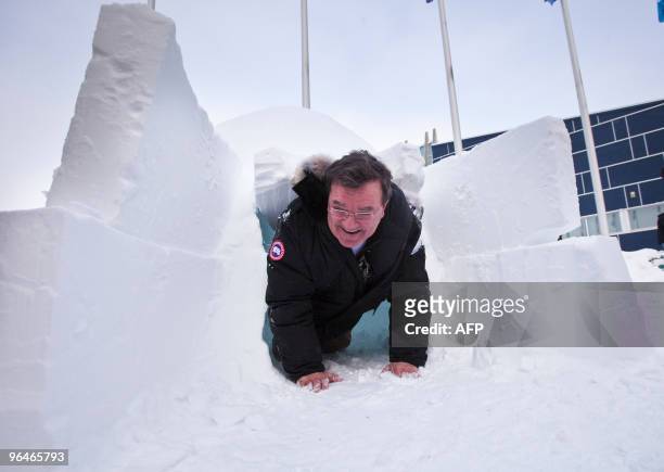 Canada's Finance Minister Jim Flaherty dislodges a block of snow as he exits an igloo outside the Nunavut legislature in Iqaluit, Canada during a...