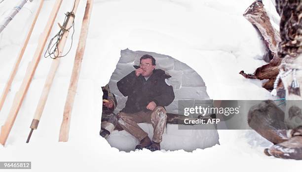 Canada's Finance Minister Jim Flaherty tastes a piece of fish inside an igloo which has been constructed outside the Nunavut legislature in Iqaluit,...