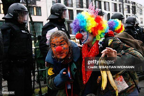 Two protestors dressed up as clowns walk past riot police during a demonstration against the 46th Munich Security Conference in Munich, southern...