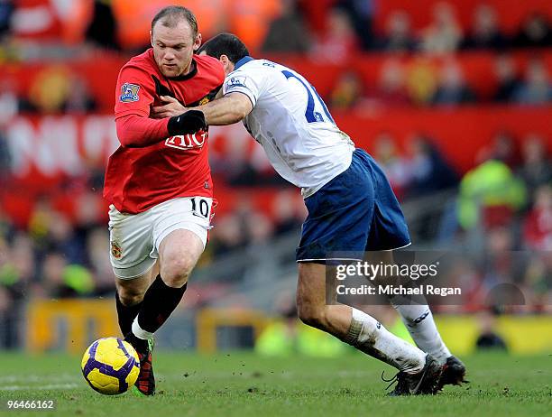 Wayne Rooney of Manchester United is challenged by Tal Ben Haim of Portsmouth during the Barclays Premier League match between Manchester United and...