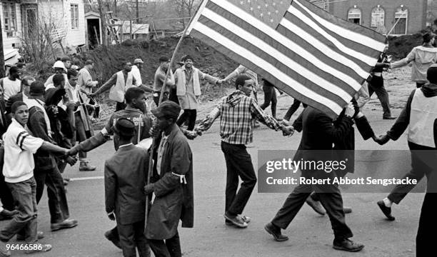 Marchers, hand in hand, walk past a fellow marcher waving an American flag, during the Selma to Montgomery march, held in support of voter rights,...
