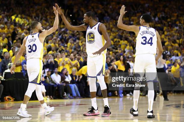 Stephen Curry of the Golden State Warriors celebrates with Kevin Durant and Shaun Livingston against the Cleveland Cavaliers in overtime during Game...