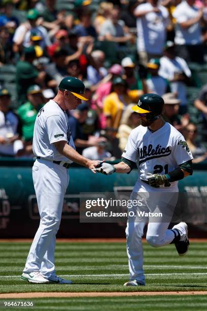 Jonathan Lucroy of the Oakland Athletics is congratulated by third base coach Matt Williams after hitting a home run against the Arizona Diamondbacks...
