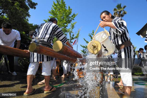 People wearing happi, festival clothes, wash the 'Kakibo' logs used to carry floats to purify during the 'Bo Arai' ritual ahead of the Hakata Gion...