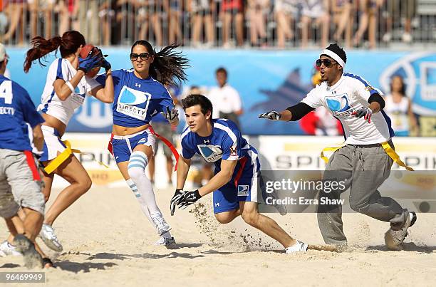 Actors Olivia Munn, Taylor Lautner and Marlon Wayans go for a tackle at the Fourth Annual DIRECTV Celebrity Beach Bowl at DIRECTV Celebrity Beach...