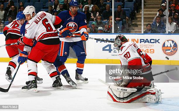 Goaltender Justin Peters of the Carolina Hurricanes deflects the puck as teammate Tim Gleason looks on in a game against the New York Islanders on...