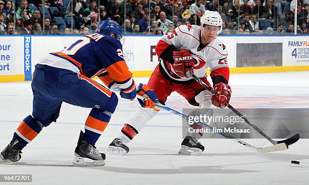 Joni Pitkanen of the Carolina Hurricanes passes the puck past Sean Bergenheim of the New York Islanders on February 6, 2010 at Nassau Coliseum in...