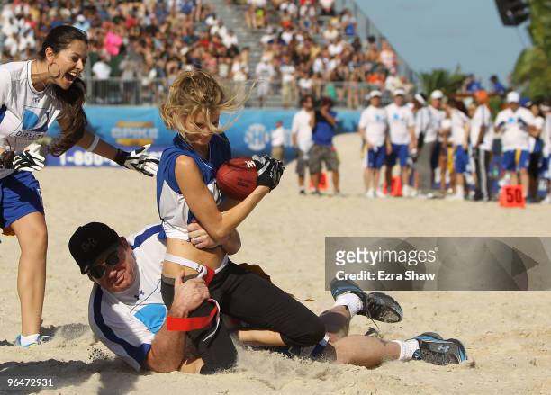 Model Marisa Miller is tackled by actor Tom Arnold at the Fourth Annual DIRECTV Celebrity Beach Bowl at DIRECTV Celebrity Beach Bowl Stadium: South...