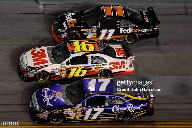 Matt Kenseth, driver of the Crown Royal Ford, races Greg Biffle, driver of the 3M Ford, and Denny Hamlin, Driver of the FedEx Express Toyota, during...