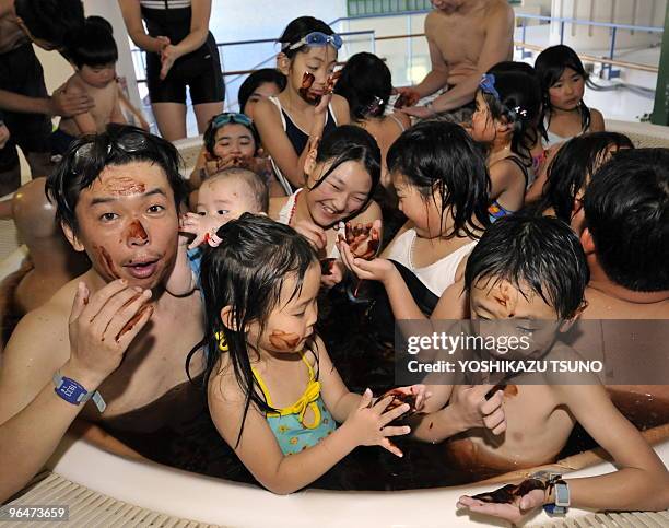 Visitors dab chocolate syrup on their faces at a "chocolate spa" at the Hakone Yunessun spa resort in Hakone town, Kanagawa prefecture, 100 km west...