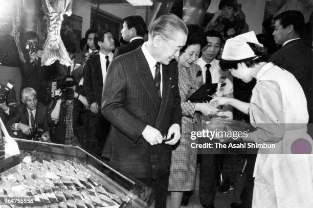 Japanese Prime Minister Noboru Takeshita and his wife Naoko purchase two packs of three slices of salted salmon, pay 2,060 yen including tax, on the...