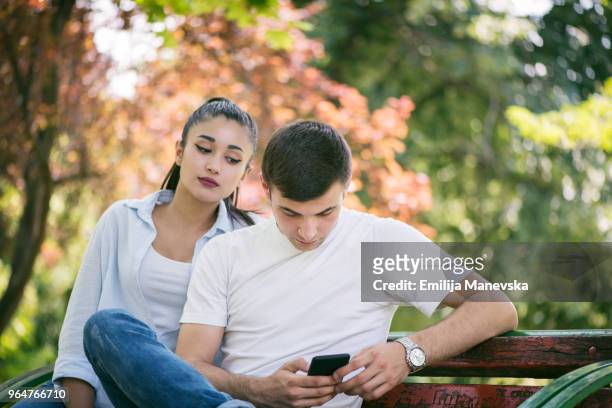 young woman spy on boyfriend cell phone - secluded couple stockfoto's en -beelden