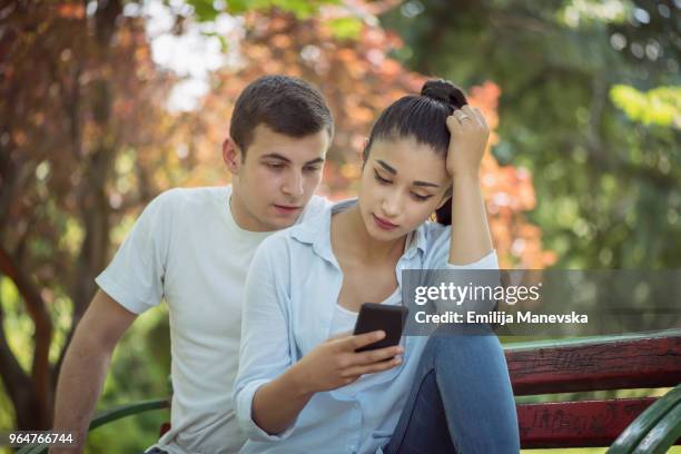 young man spy on girlfriend's cell phone - hypocrisy stock pictures, royalty-free photos & images