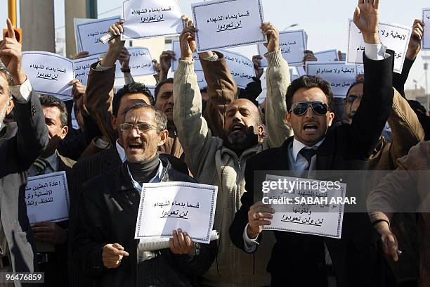 Iraqi men shout slogans and hold signs that read in Arabic "We swear by the blood of martyrs, you will not return" during a protest in Baghdad on...