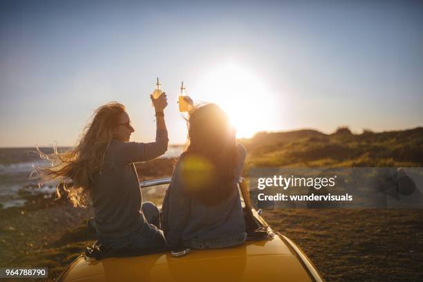 women with cabriolet car relaxing and drinking soda at beach - drinking soda in car stock pictures, royalty-free photos & images