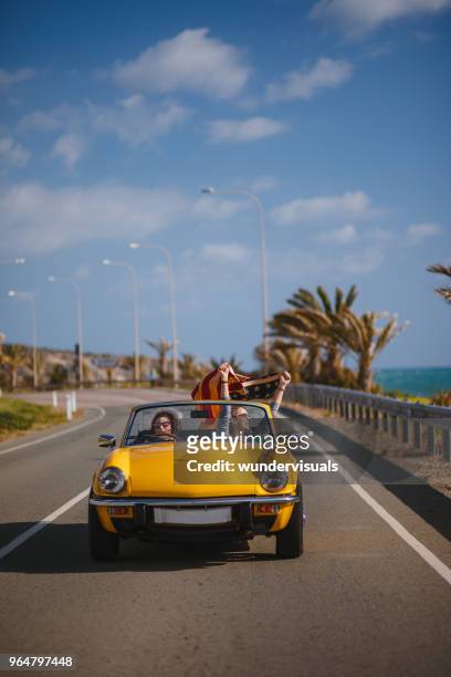 young hipster girls with american flag driving vintage convertible car - american flag beach stock pictures, royalty-free photos & images