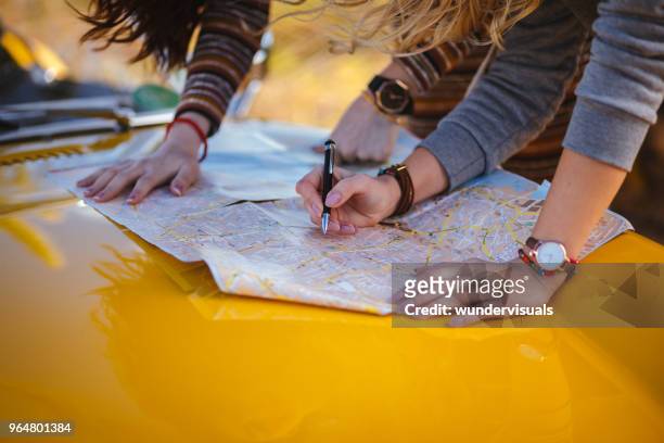 frauen auf sommer roadtrip lesen karte nach dem weg - navigationsinstrument stock-fotos und bilder