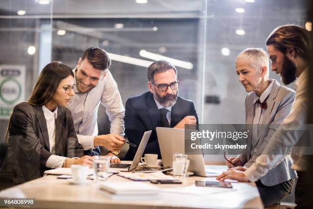 equipe de negócios cooperando enquanto trabalhava em laptops no escritório. - reunião de equipe - fotografias e filmes do acervo