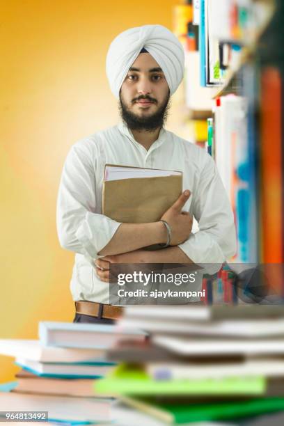 sikh man holding a textbook - all india sikh students stock pictures, royalty-free photos & images