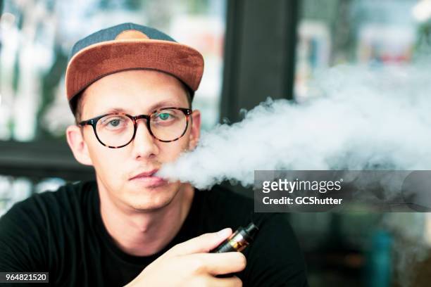 hombre caucásico vaping en un café al aire libre - vaping fotografías e imágenes de stock