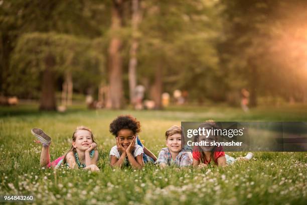bambini felici che si divertono nella giornata primaverile mentre giacciono sull'erba e distovano lo sceno - solo bambini foto e immagini stock