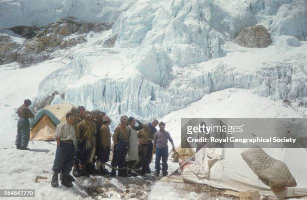Sherpas at Camp IV standing behind a line of rubbish and looking up, Nepal, March 1953. Mount Everest Expedition 1953.