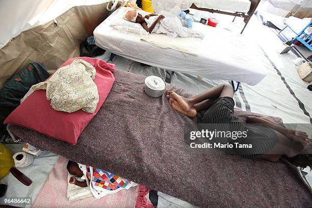 Patients are seen at a Doctors Without Borders hospital as a baby sleeps February 7, 2010 in Leogan, Haiti. Leogan is located close to the epicenter...