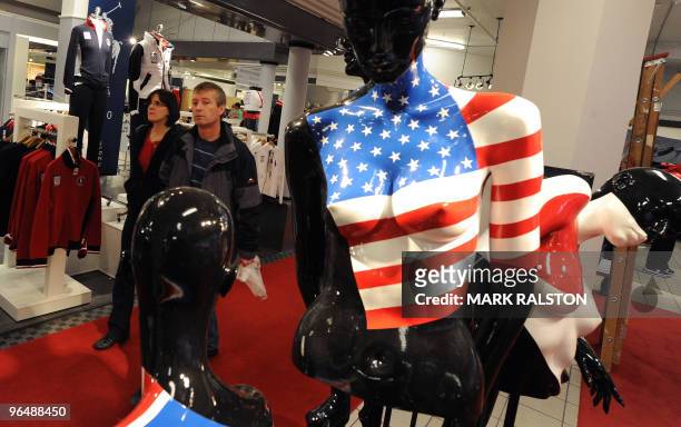 Couple walk past a mannequin decorated with the US flag promoting Winter Olympic team merchandise at the Hudson's Bay department store in downtown...