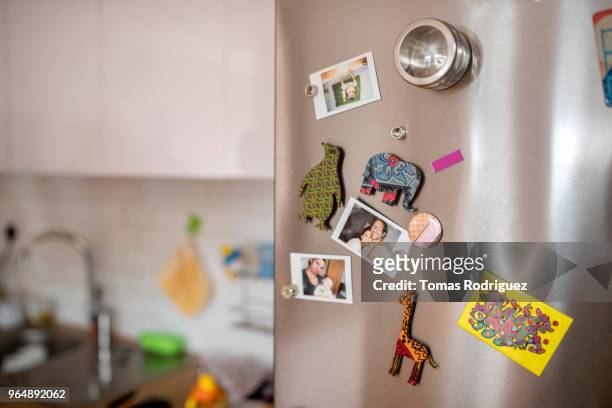 fridge door with colored magnets and polaroid images - refrigerator stock-fotos und bilder