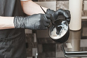 Hair stylist hands preparing a dye in a container
