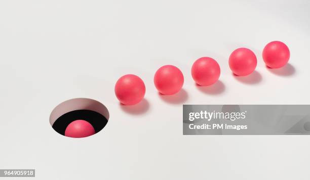 line of red balls heading towards a hole - skill gap stock pictures, royalty-free photos & images