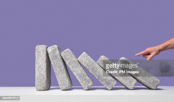 man's hand starting domino effect - baksteen stockfoto's en -beelden