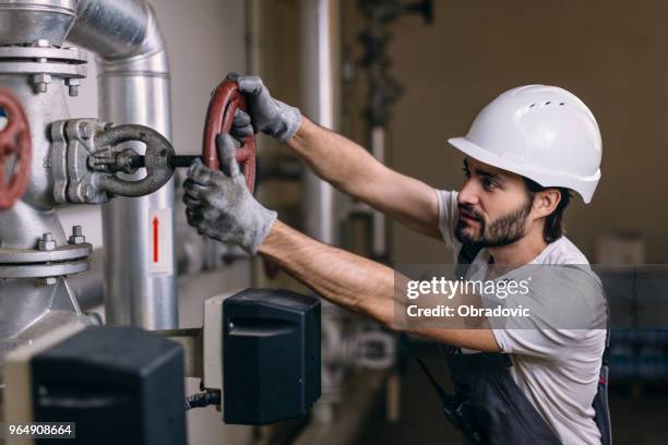 worker with helmet in front of pipes with valves - distillation tower stock pictures, royalty-free photos & images