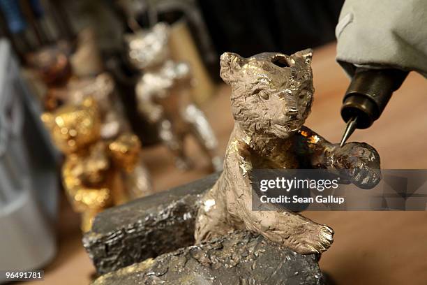 Berlinale Bear lies clamped in a vice as a metal crafts worker shaves off casting remains from its arm while finished and semi-finished bears stand...