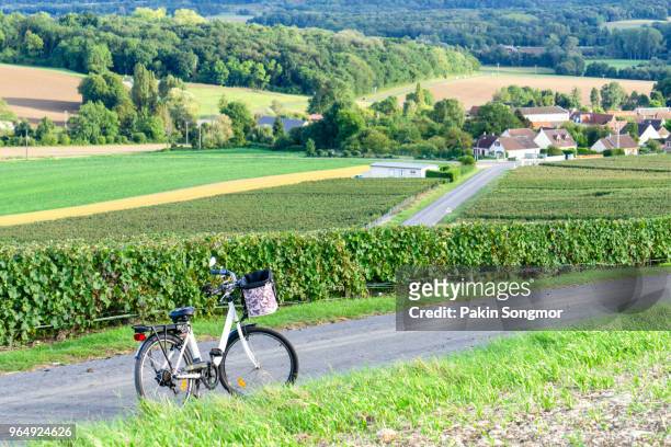 bicycle on the road in champagne vineyards at montagne de reims countryside village background - montagne route stock-fotos und bilder
