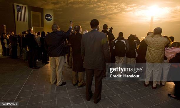 In this handout image provided by NASA, guests look on from the terrace of Operations Support Building II as space shuttle Endeavour launches at the...